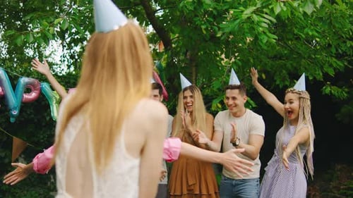 Young Woman Covers Her Friend's Eyes with Her Hands Leading Her to a Surprise Birthday Party with