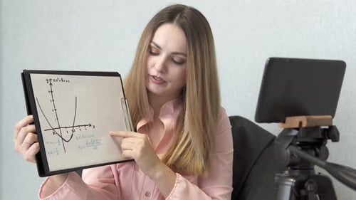 A math teacher conducts an online lesson with high school students via a tablet.