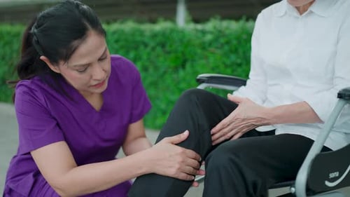 Caring Nurse Helping Senior Woman with Knee Therapy
