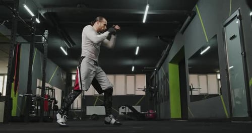 Full Body Man in Sportswear Performing Kicks and Punches Into Air While Shadow Boxing in Modern Gym