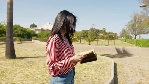 Woman Standing In The Park Reading A Book