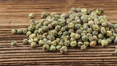 Dried green peppercorn. Dry green pepper spice on wooden table.