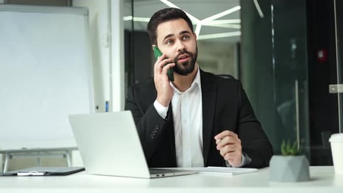 Man in Suit Talking on Phone, Taking Notes