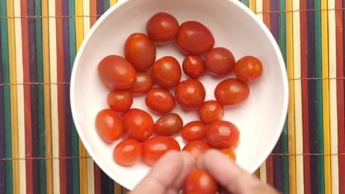 Fresh Tomatoes Being Added to a White Bowl