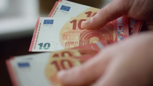 Las manos del hombre cuentan de cerca los pequeños ahorros en interiores. Joven trabajador desconocido calculando billetes en euros para...