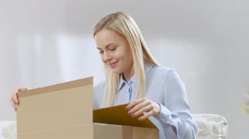 Woman Excitedly Opens a Box at Home