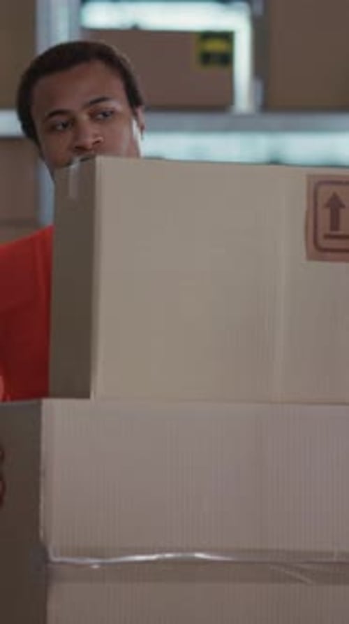 Young Adult Male Carrying Cardboard Boxes in Warehouse