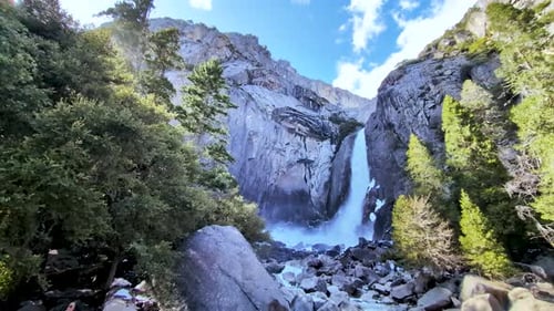 Majestic waterfall in Yosemite National Park cascading down a granite cliff, surrounded by lush gree
