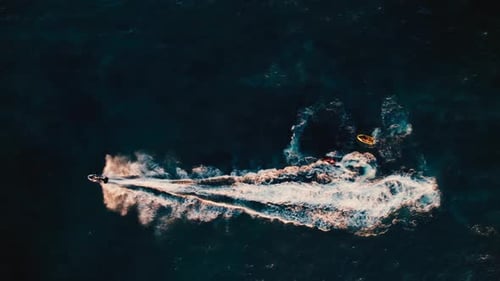 Three jet skis create waves in a vibrant blue ocean during a sunny afternoon on the coast