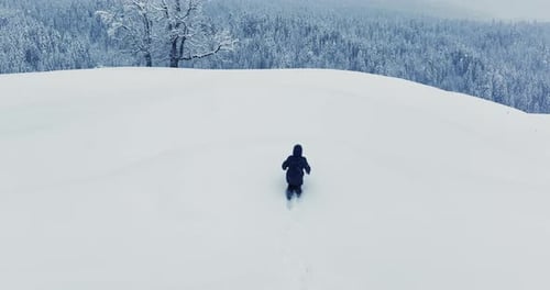 Hiker Walking in Deep Snow Outdoors in Forest Landscape