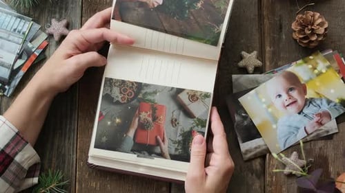 Mujer que imprime fotos navideñas mira un álbum de fotos con fotos impresas