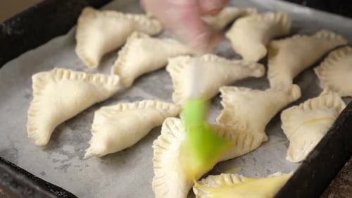 23, Raw pies are poured with liquid egg before baking. Cooking pies.