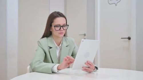 Woman Working on Tablet at Table Indoors