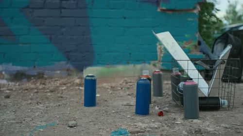 Tintas e esboços em spray no chão ao lado da parede de grafite