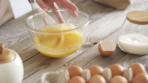 Beating chicken eggs to prepare the dough. Mixing chicken egg yolks in a transparent glass bowl Tray
