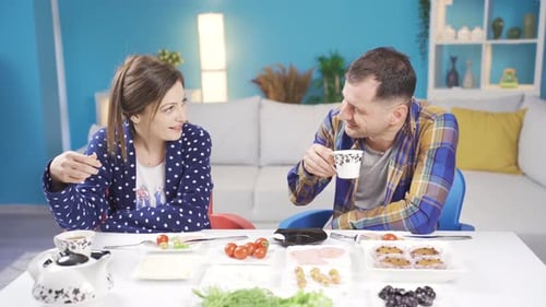 Cheerful and funny married couple are having breakfast at home.