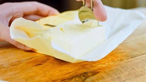 The Woman Takes a Spoonful of Butter From the Square Package
