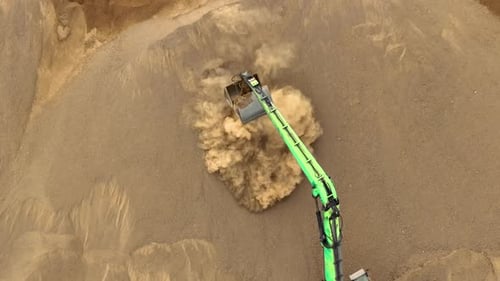 Excavator Scooping Sand From a Large Pile