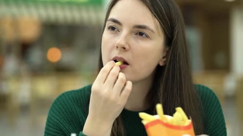 Young Woman Enjoys French Fries and Beverage
