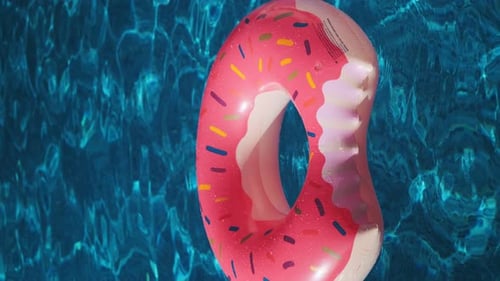 Anel inflável rosa na água de uma piscina em um dia ensolarado. Conceito de férias de verão. Rosquinha é