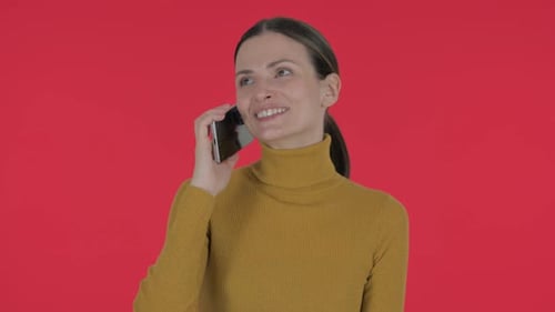 Woman Talking on Cellphone in Front of Red Background