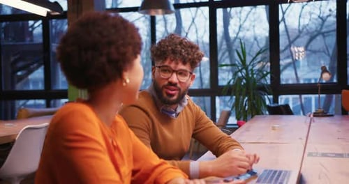 Smiling Happy Multinational Woman and Man Sitting and Working in Modern Office Talking Using Laptop