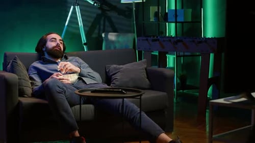 Man Relaxing on Sofa Eating Popcorn at Night