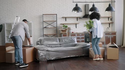 Couple Carrying Moving Boxes Into New Apartment