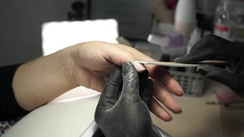 Close up view. Manicurist works with nail file in a beauty salon.