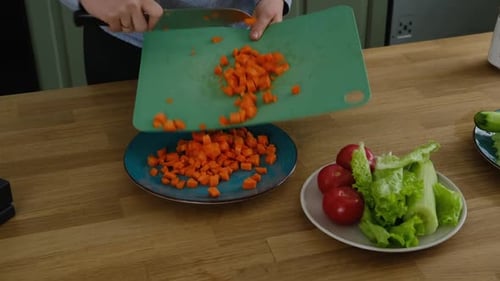 Nahaufnahme einer Frau, die Gemüse in einer Küche hackt, weibliche Hände beim Schneiden von Tomaten und Karotten auf dem Brett