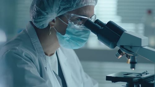 Woman Scientist Uses Microscope in Bright Lab