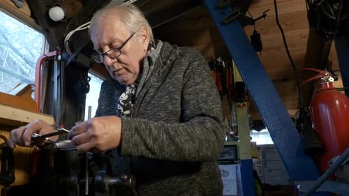 Senior mechanic uses Vernier caliper to measure part held in a bench vice