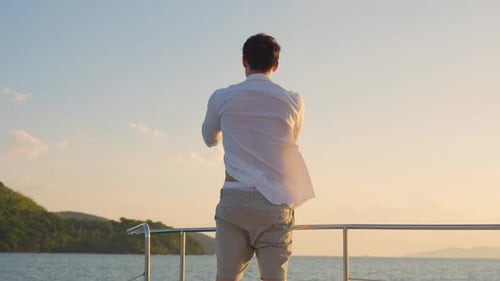 Young Man Using Smartphone on Boat Near Coast