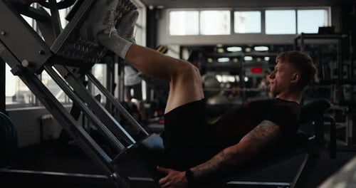 Side View of a Confident Guy Athlete in a Black Sports Uniform with Tattoos and in Gray Sneakers