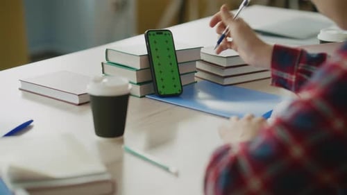 Student nutzt Smartphone mit Greenscreen während der Vorlesung