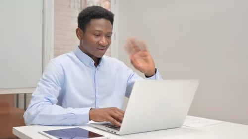 African Businessman Chatting Online on Laptop while Sitting in Office