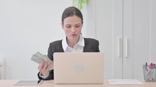 Businesswoman Counting Money at Office Desk