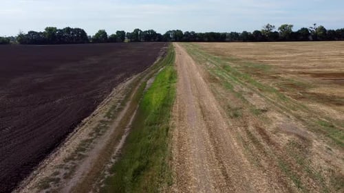 Flight Over Dirt Road Between Field Plowed Earth Field After Straw Harvesting