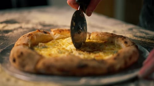 Close Up in a Professional Kitchen in Pizzeria the Chef Cuts the Pizza Into Pieces with a Round