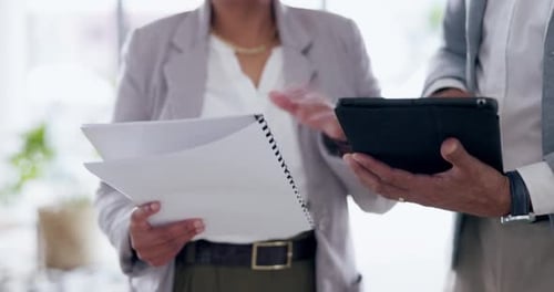 Two people look at documents and tablet indoors