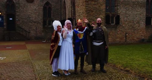 Variety of fairy tale characters waving while standing in front of a medieval castle