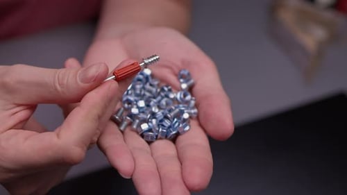 Closeup of Worker Hands Inspecting Small Industrial Hardware Components Holding Redtipped Screwin