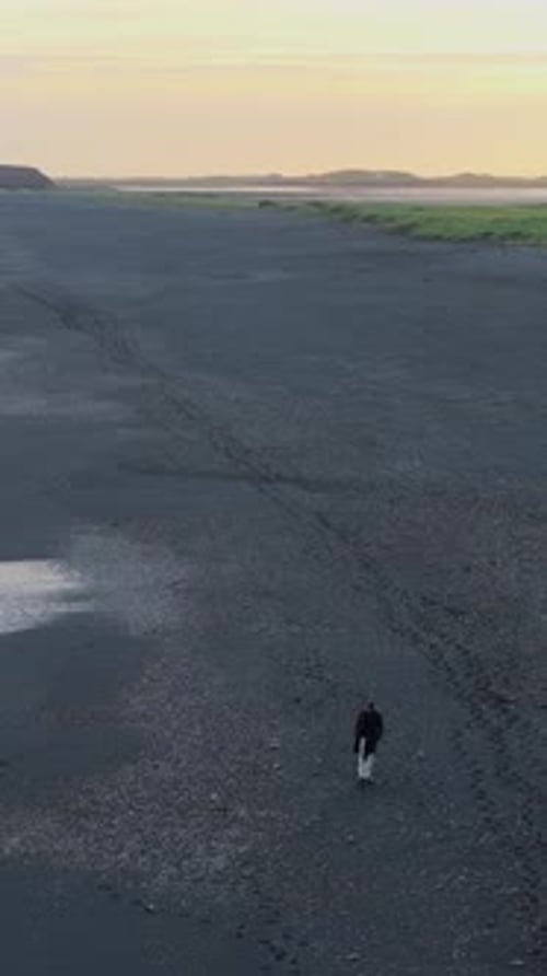 Lone Walker on Black Sand Beach at Sunrise