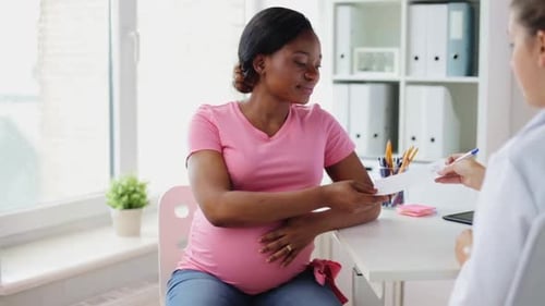 Pregnant Woman Talking with Doctor in Medical Office