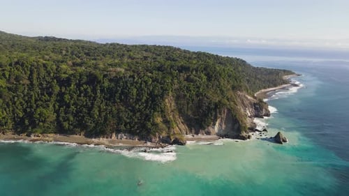 Slow aerial view of an ocean cliff and turquoise waters in Osa Peninsula, Costa Rica