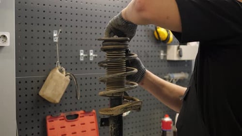 Ein Mechaniker repariert Autostoßdämpfer an einer Autostation Er entfernt die Feder