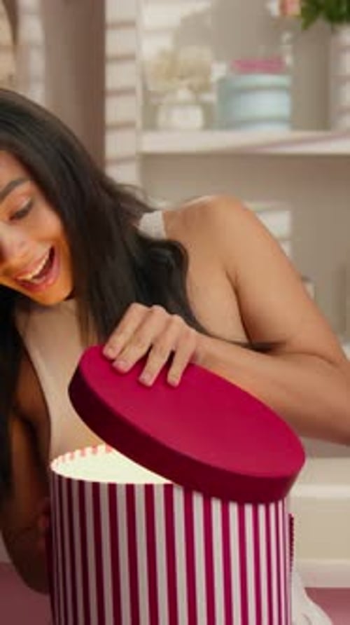 Surprised Young Woman Opening a Glowing Gift Box at Home