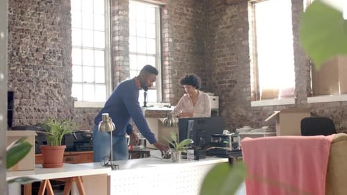 Diverse colleagues unpacking boxes with documents and office items in creative office in slow motion
