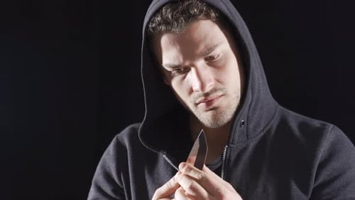 Vagrant psycho man looking at camera with knife in hand.