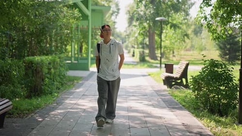 Teenage Male Wandering Along Shaded Park Trail with Backpack Young Individual Casually Exploring